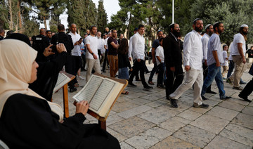 Jewish visitors walk past people reading the holy Quran, at the compound that houses Al-Aqsa Mosque in Jerusalem. (REUTERS)